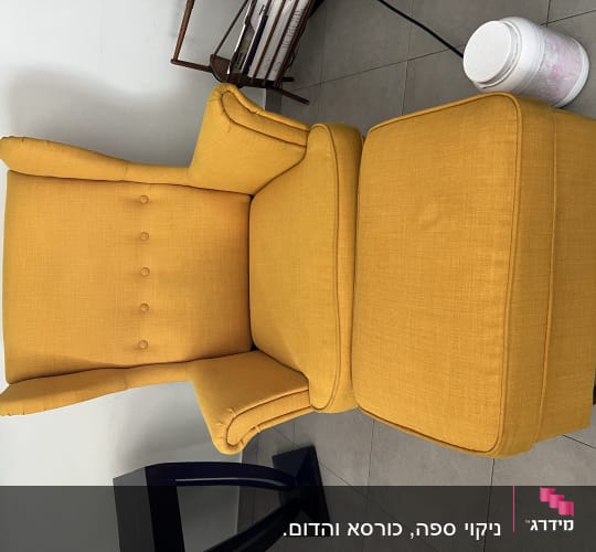 כורסה צהובה עם הדום על רצפת אריחים אפורה
